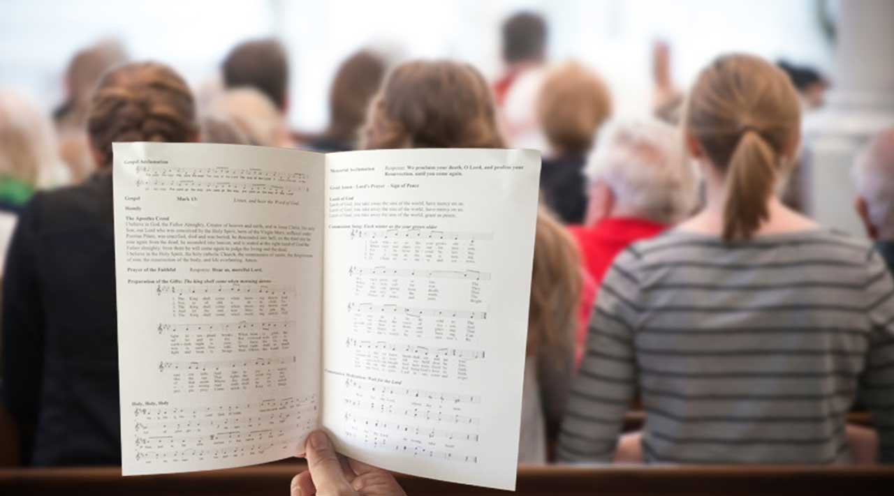Person holding a worship booklet in a church congregation